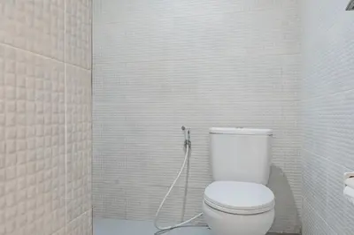a bathroom with a toilet with a hose at Collection O Kuta Near Airport Ngurah Rai in Kuta