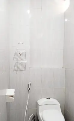 a white bathroom with a toilet and a sink at Tambak Sari Villa in Jimbaran