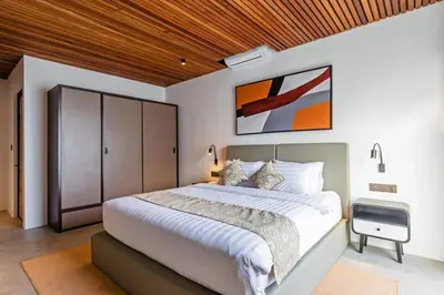 a bedroom with a large white bed with a wooden ceiling at Manresa Villa Bali 4 in Canggu