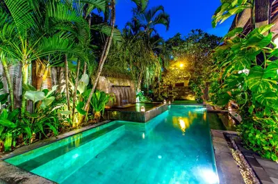 a swimming pool in a backyard with palm trees at Villa Taksu Legian in Legian