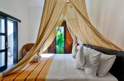 a bedroom with a canopy bed with white pillows at Villa Taksu Legian in Legian