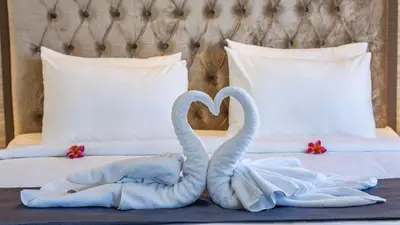 two swansrendered to look like they are making a heart on a bed at City of Aventus Hotel - Denpasar in Denpasar