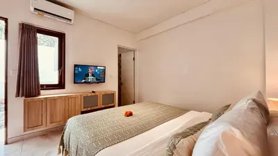 a bedroom with a bed and a flat screen tv at Ellavie Aparthouse Kerobokan in Kerobokan