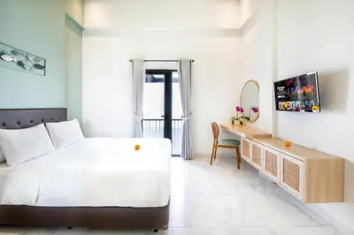 a bedroom with a bed and a desk with a mirror at Ellavie Aparthouse Kerobokan in Kerobokan