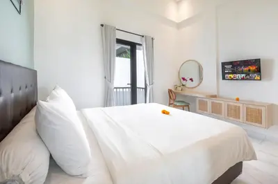 a white bedroom with a large white bed and a mirror at Ellavie Aparthouse Kerobokan in Kerobokan