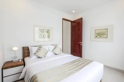 a bedroom with a white bed and a wooden door at Vienna Villas by Great Bali Villas in Seminyak