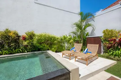 a backyard with two chairs and a swimming pool at Freshly Renovated 3 BD Homey Central Villa in Seminyak