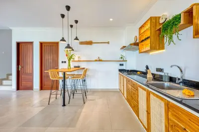a kitchen with wooden cabinets and a table with chairs at Freshly Renovated 3 BD Homey Central Villa in Seminyak