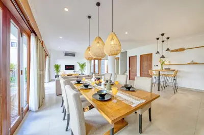 a dining room and living room with a wooden table and chairs at Freshly Renovated 3 BD Homey Central Villa in Seminyak