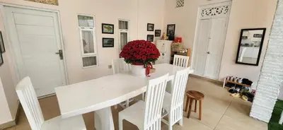 a white dining room table with a vase of red flowers at Capricorn Villa in Seminyak