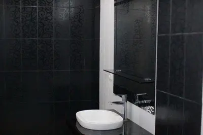 a bathroom with a toilet and a black wall at Capricorn Villa in Seminyak