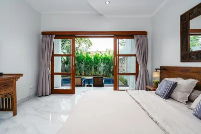 a bedroom with a bed and sliding glass doors at Villa Putih Jimbaran in Jimbaran