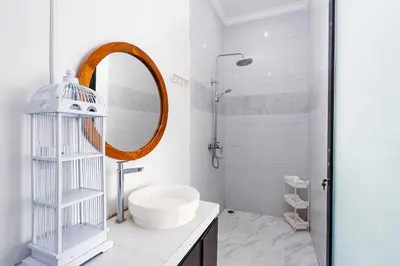 a white bathroom with a sink and a mirror at Villa Putih Jimbaran in Jimbaran
