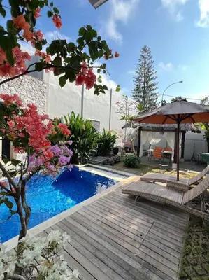 a swimming pool with a wooden deck and an umbrella at 2 BR Pepper House Villa near GWK Jimbaran - garden view in Jimbaran