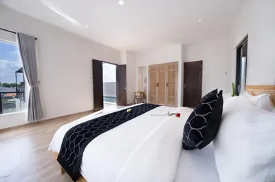 a bedroom with a large white bed with black pillows at Canggu Villa Go by Nagisa Bali in Canggu