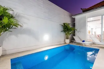 a swimming pool in a room with a white wall at Luxury minimalist villa Nobu in Seminyak in Seminyak