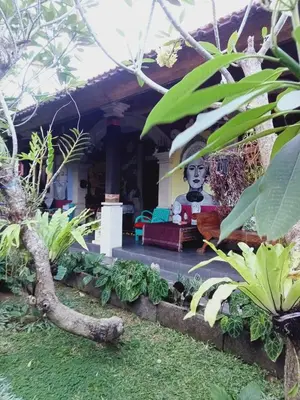 a garden in front of a house with a statue at Buratwangi Tropis House in Kerobokan