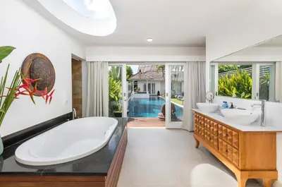 a bathroom with a tub and two sinks and a pool at Kerta Rama Seminyak by Kerta Living in Seminyak