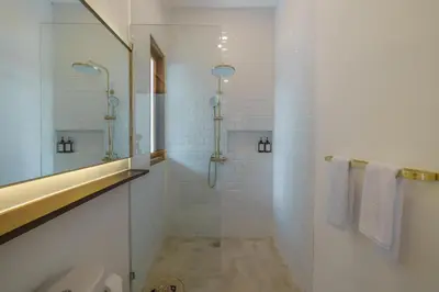 a white bathroom with a shower and a sink at Villa Umaju - Contemporary Minimalist 2BR Villa in Umalas! in Canggu