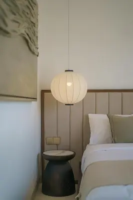 a bedroom with a bed and a table and a lamp at Villa Umaju - Contemporary Minimalist 2BR Villa in Umalas! in Canggu