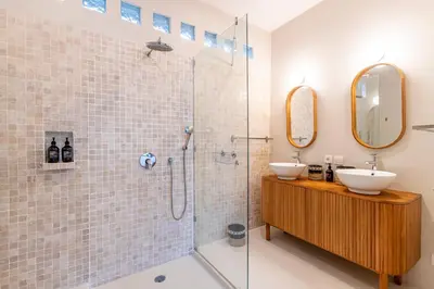 a bathroom with a shower and a sink and a mirror at Villa Elea - Bright & Modern 2BR Villa in Seminyak with Private Pool and Sunset Rooftop in Seminyak