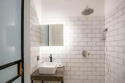 a white bathroom with a sink and a mirror at Town House REX in Kuta