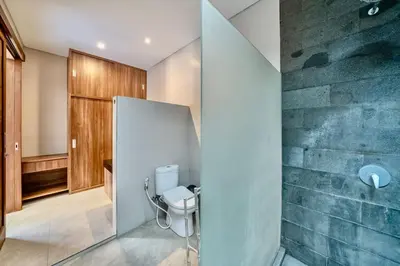 a bathroom with a toilet and a stone wall at Exclusive 2BR Villa with bathroom en suite and privat Pool in Kerobokan