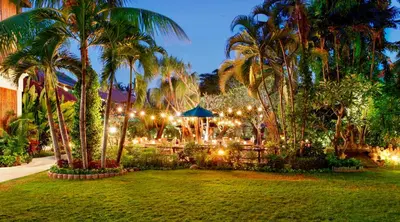 a garden with palm trees and lights in a park at Astagina Resort Villa and Spa in Legian