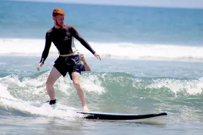 a man riding a wave on a surfboard in the ocean at Astagina Resort Villa and Spa in Legian