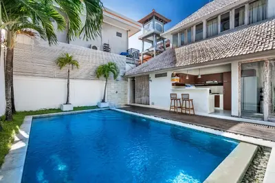 a pool in front of a house with palm trees at Villa Oberoi in Seminyak