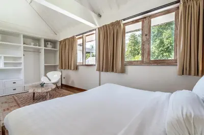 a bedroom with a white bed and two windows at Villa Oberoi in Seminyak
