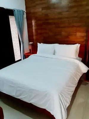 a large white bed in a bedroom with a wooden headboard at St.Regina Bali 3 Bedroom Villa in Nusa Dua