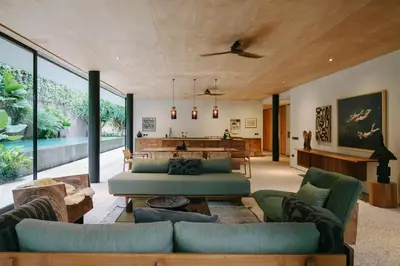 a living room with blue couches and a table at Sandhouse Berawa in Canggu