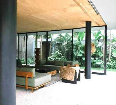 a living room filled with furniture and glass windows at Sandhouse Berawa in Canggu