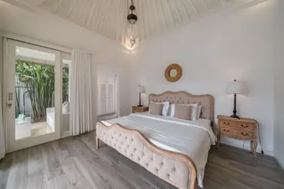 a white bedroom with a large bed and a window at Beachside Colonial Elegance: 4BR in Canggu in Canggu