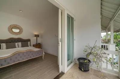 a bedroom with a bed and a sliding glass door at Beachside Colonial Elegance: 4BR in Canggu in Canggu