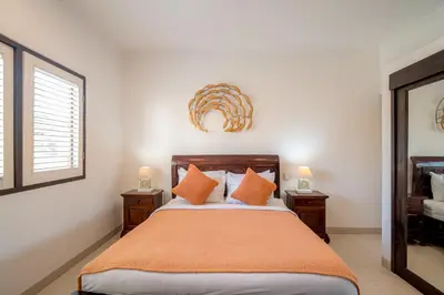 a bedroom with a bed with orange pillows and a mirror at Sari Temuku Villa in Seminyak