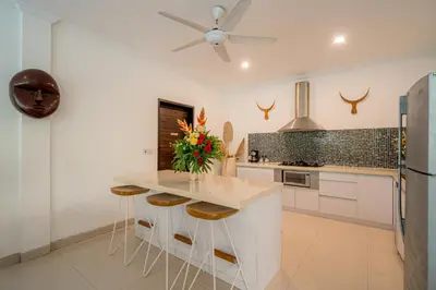 a kitchen with a counter with stools and a refrigerator at Sari Temuku Villa in Seminyak
