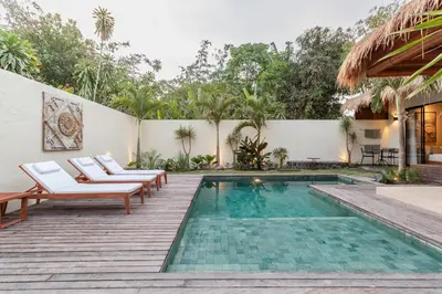 a swimming pool with chairs and a fence and a house at Villa Jodoh - Exciting Chic 4BR Stylish Villa Near Seminyak, Perfect for a Trendy Getaway in Kerobokan