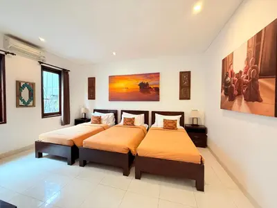 two beds in a room with paintings on the wall at Villa Penelopy in Seminyak