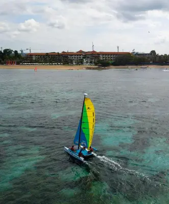a person riding a small sail boat in the water at Grand Mirage Resort & Thalasso Bali - All Inclusive in Nusa Dua