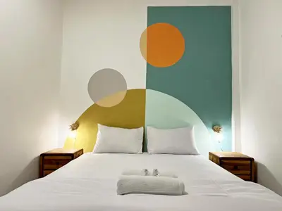 a bedroom with a white bed with a colorful wall at Villaok in Kuta