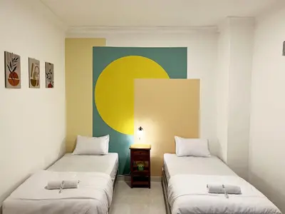two beds in a room with a painting on the wall at Villaok in Kuta