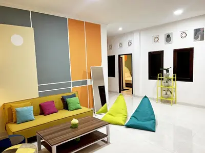 a living room with a yellow couch and colorful pillows at Villaok in Kuta