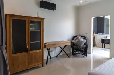 a bedroom with a wooden cabinet and a chair at Villa Cantik in Canggu