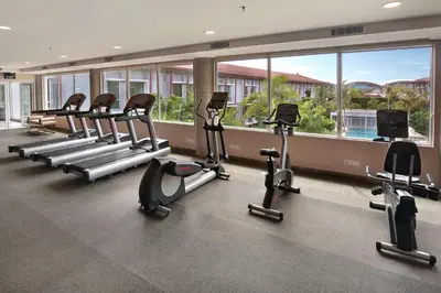 a gym with a row of treadms and elliptical machines at Hilton Garden Inn Bali Ngurah Rai Airport in Kuta