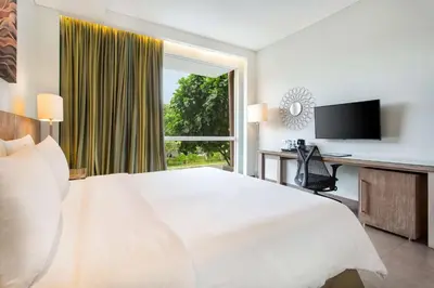 a white bedroom with a large bed and a window at Hilton Garden Inn Bali Ngurah Rai Airport in Kuta