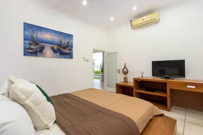 a bedroom with a bed and a flat screen tv at Buddha Beach Villa Seminyak in Seminyak