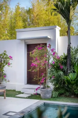 a white house with flowers and a swimming pool at Villa Pawikan Gorgeous 4 beds villa in the heart of Seminyak in Seminyak
