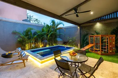 a patio with a table and chairs and a swimming pool at Central 3bd Modern Villa with Private Pool and Play Area in Kerobokan